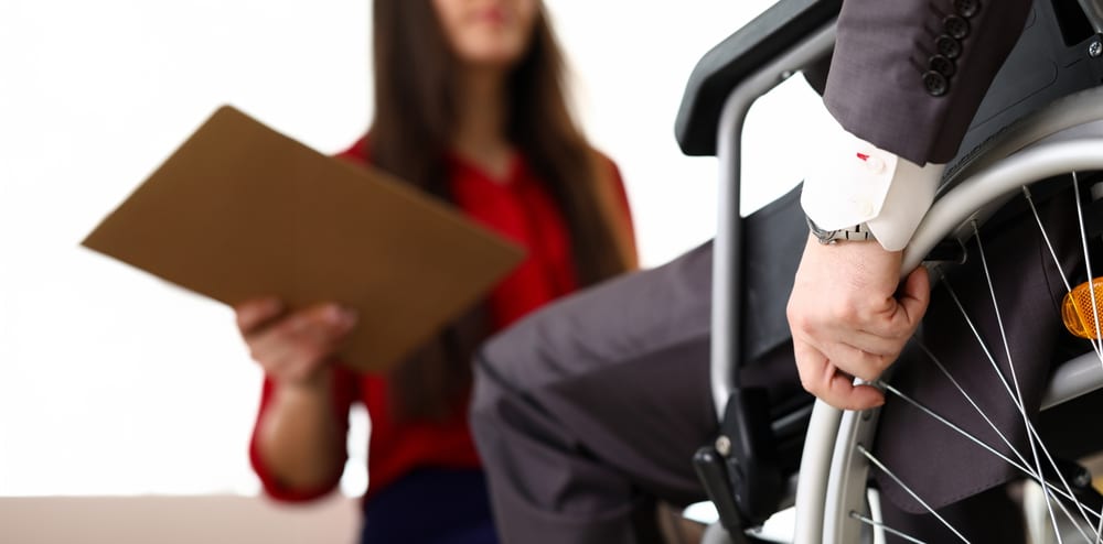 Man in suit on wheelchair communicates with woman